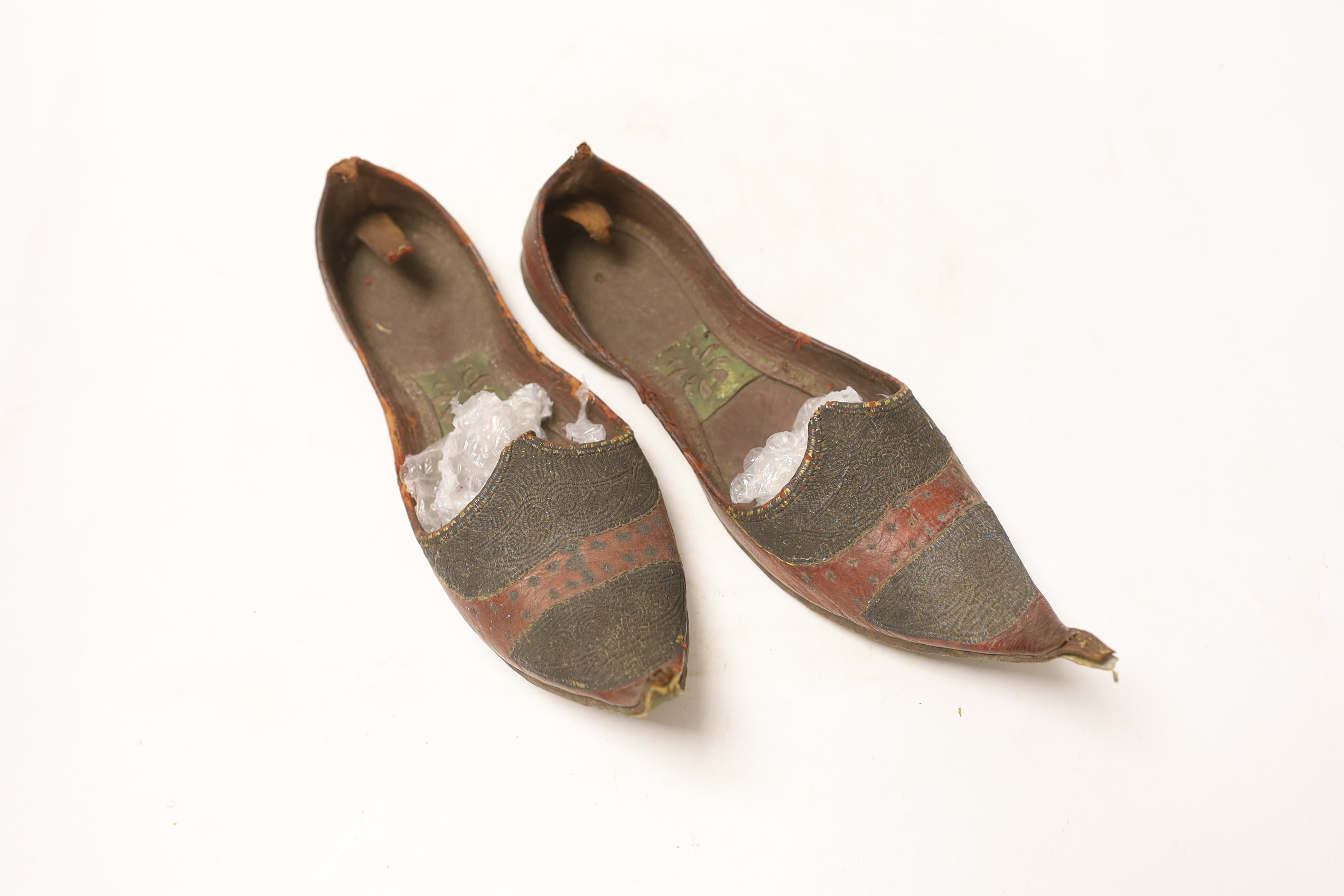 Two pairs of shoes; a small pair of novelty carved wooden heeled clogs with Philippine’s 1945 painted on the back of the heels and a carved house and mountainous scene within the heel and sole, together with a pair of le